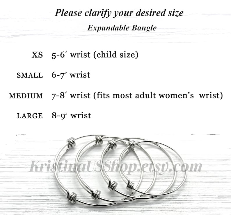 May include: Four expandable silver bangles in different sizes. The sizes are labeled as XS, Small, Medium, and Large. The sizes correspond to wrist sizes of 5-6 inches, 6-7 inches, 7-8 inches, and 8-9 inches. The bangles are on a white wooden surface.