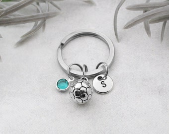 May include: Silver keychain with a soccer ball charm, a teal blue crystal charm, and a silver charm with the letter "S".