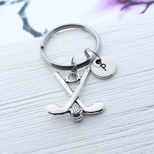 May include: Silver golf club keychain with a golf ball charm and a silver letter 'P' charm attached to a silver key ring.