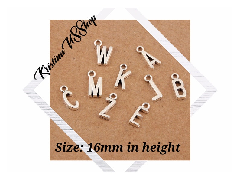 May include: Silver-colored metal alphabet charms, including letters W, M, K, L, B, A, C, Z, and E, are displayed on a brown card. The charms are approximately 16mm in height. The shop name "Kristina USShop" is in the upper left corner.