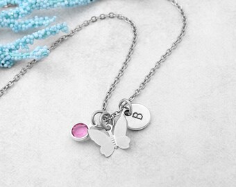 Könnte beinhalten: Eine silberne Kettenkette mit einem Schmetterlingsanhänger, einem rosa Kristall und einem silbernen Scheibenanhänger mit dem eingravierten Buchstaben "B".
