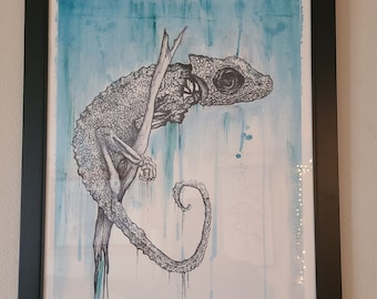 May include: A black and white drawing of a chameleon on a branch, with a blue watercolor background. The chameleon is hanging upside down, with its tail curled around the branch. The drawing is signed "DZA" in the bottom right corner.