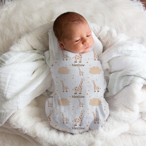 May include: A white swaddle with a giraffe and star pattern. The swaddle is personalized with the name "Matthew".
