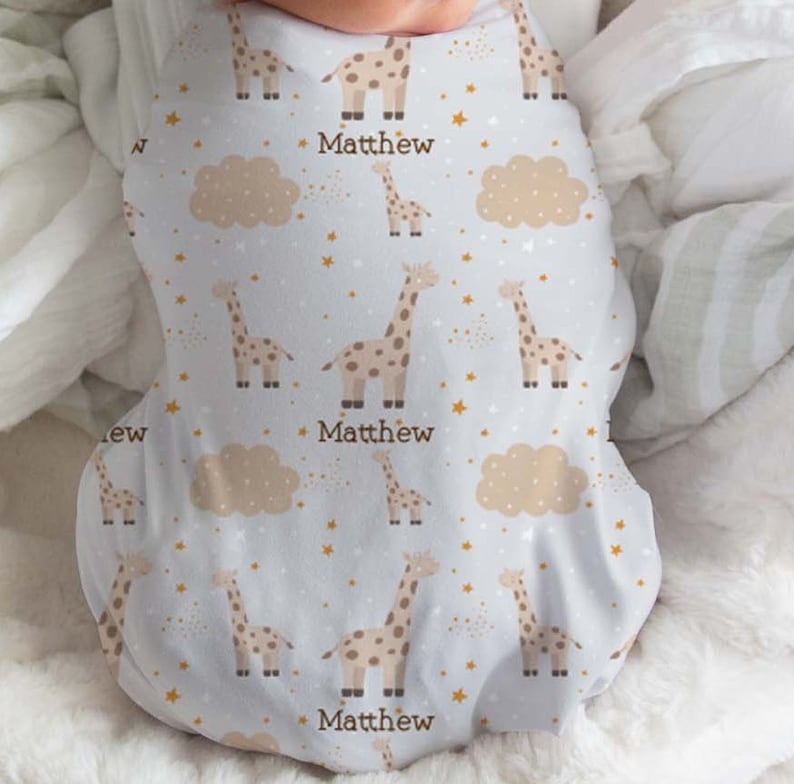 May include: White baby sleeper with a pattern of brown giraffes, gold stars, and beige clouds. The sleeper has the name "Matthew" printed three times on the front.