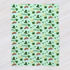 May include: A green and white baby blanket with a repeating pattern of shamrocks, rainbows, leprechaun hats, and gold horseshoes. The name "Bailey" is repeated throughout the pattern.