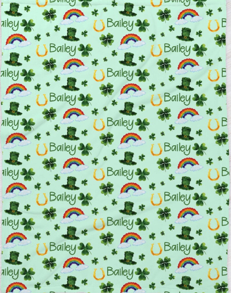 May include: A green and white fabric with a repeating pattern of rainbows, shamrocks, horseshoes, and leprechaun hats. The name Bailey is repeated throughout the pattern.