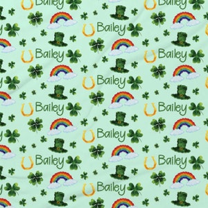 May include: A green fabric with a repeating pattern of rainbows, shamrocks, horseshoes, and leprechaun hats. The name Bailey is repeated throughout the pattern.