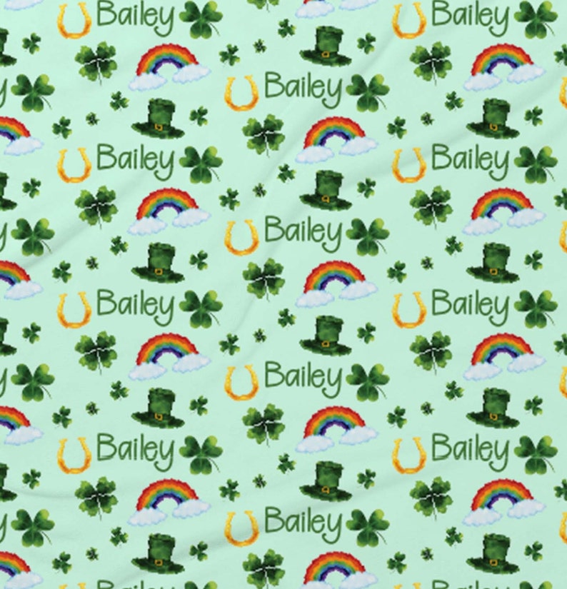 May include: A green fabric with a repeating pattern of rainbows, shamrocks, horseshoes, and leprechaun hats. The name Bailey is repeated throughout the pattern.