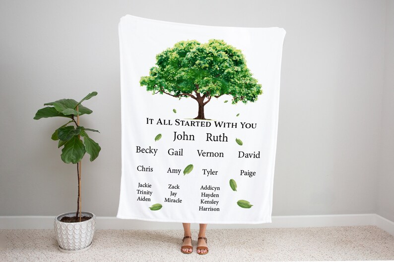 May include: A white blanket with a green tree design and the text "It all started with you" at the top. The tree has leaves falling from it and names written on the branches. The names are John, Ruth, Becky, Gail, Vernon, David, Chris, Amy, Tyler, Paige, Jackie, Zack, Addicyn, Trinity, Jay, Hayden, Aiden, Miracle, Kensley, and Harrison.