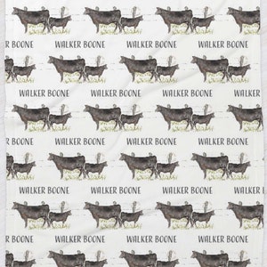 K&ouml;nnte beinhalten: Ein wei&szlig;er Stoff mit einem sich wiederholenden Muster aus schwarzen K&uuml;hen und dem Text "WALKER BOONE".