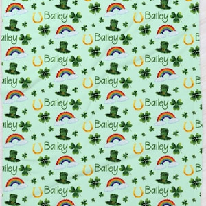 May include: A green and white patterned baby blanket with a rainbow, shamrock, and horseshoe design. The name "Bailey" is repeated throughout the pattern.