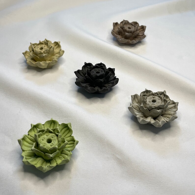 Puede incluir: Colecci&oacute;n de cinco porta inciensos con forma de flor de loto en varios colores. Los soportes son en tonos verdes, negros, beige y grises. El dise&ntilde;o de la flor de loto es detallado, con p&eacute;talos visibles y un agujero central para el incienso.