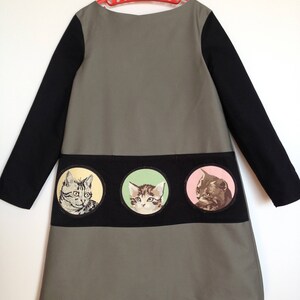 Paint-by-numbers style cats decorate 3 deep pockets on a long-sleeved gray and black dress.