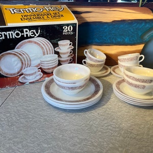 May include: A 20-piece Termo-Rey dinnerware set. The set includes plates, bowls, cups, and saucers with a white base and a brown dotted border. The box is yellow and black with the brand name and product details.