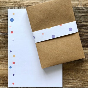 May include: A white card with a brown envelope. The card has a pattern of small, colorful dots along the left edge. The envelope has a white band with a pattern of small, colorful dots.