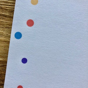 May include: A white sheet of paper with a row of colored dots down the left side. The dots are purple, yellow, red, blue, purple, and red.