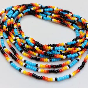May include: A long strand of seed beads arranged in a repeating pattern of bright turquoise, vibrant orange, sunny yellow, stark white, and deep black. The circular necklace features a small silver-toned metal clasp at one end to secure the strand.