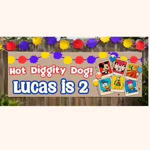 K&ouml;nnte beinhalten: Ein Geburtstagsbanner mit dem Text "Hot Diggity Dog! Lucas is 2" in Rot und Blau. Das Banner zeigt Disney-Charakterbilder und eine farbenfrohe Girlande aus roten, gelben und lila Formen.