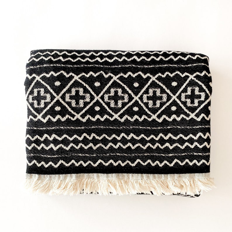 May include: Black and white throw blanket with a geometric pattern and fringe trim.