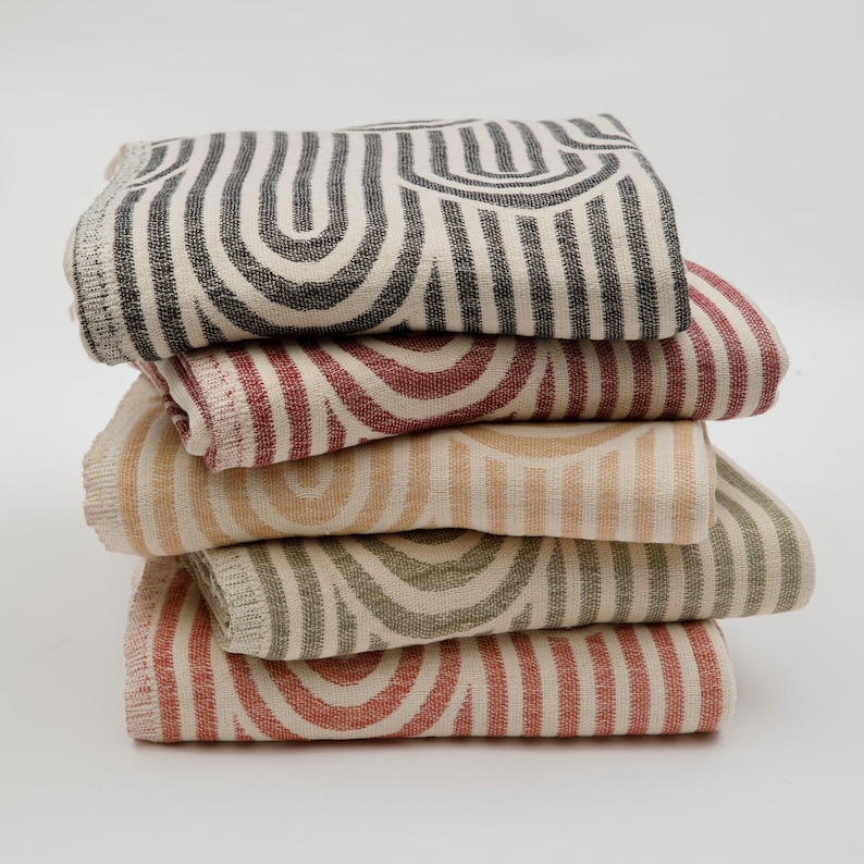 May include: A stack of five woven cotton throw blankets with a geometric pattern of black, red, beige, and green stripes and arches.