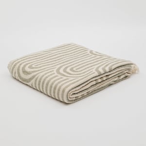May include: A folded green and white striped throw blanket with a geometric pattern.