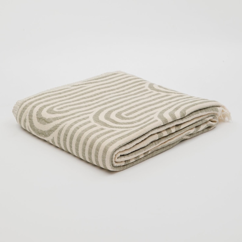 May include: A folded green and white striped throw blanket with a geometric pattern.