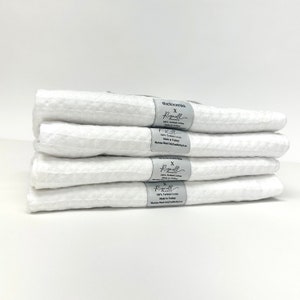 May include: A stack of five white waffle weave kitchen towels with a gray label that reads "theloomia x Rignell Home 100% Turkish Cotton Made in Turkey Machine Wash Cold Tumble Dry Low"