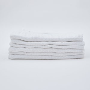 May include: A stack of six white waffle weave kitchen towels.