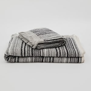 May include: A set of two black and white striped towels with fringed edges. The towels are folded and stacked on top of each other.