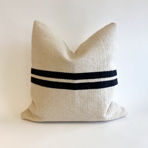 May include: A cream-colored pillow with two black stripes across the center.