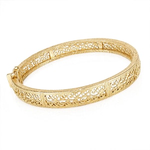 May include: A gold-toned hinged bangle bracelet featuring an intricate openwork filigree pattern with scrolling motifs. The bracelet has a textured finish and a secure clasp mechanism on one side, showcasing a continuous decorative metal design.