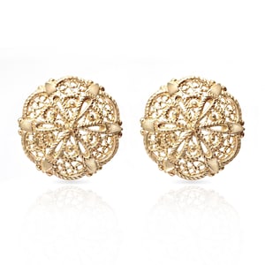 May include: A pair of round gold stud earrings featuring an intricate filigree design with a central star-like pattern and delicate openwork metal detailing. The circular earrings have a polished finish and a textured, woven appearance throughout.