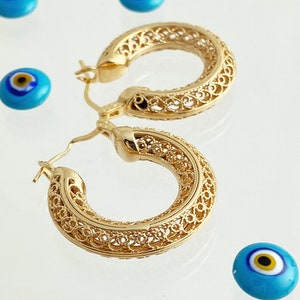 May include: A pair of gold filigree hoop earrings. The earrings are delicate and intricate, with a delicate openwork design.