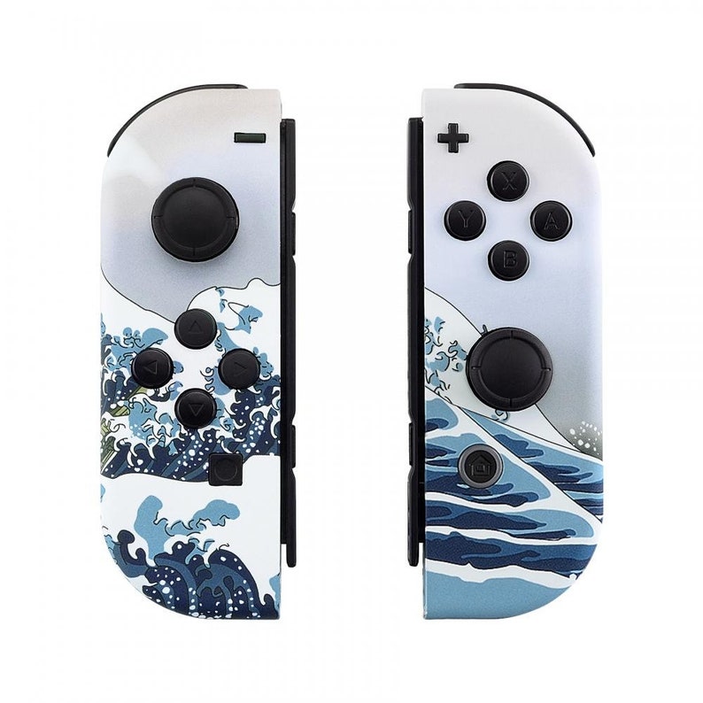 Peut inclure: Une paire de manettes Joy-Con blanches pour Nintendo Switch avec un motif de vague bleu et blanc. Les manettes comportent les boutons standard et un stick analogique noir.