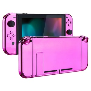 Puede incluir: Una consola Nintendo Switch de color rosa metálico con un mando Joy-Con rosa a juego. La consola está cerrada y el mando Joy-Con está conectado a la consola.