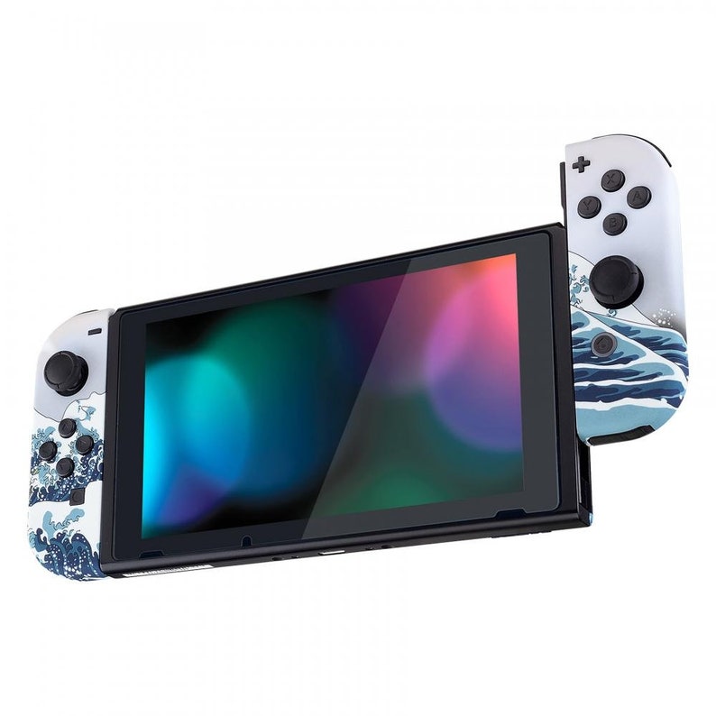 Peut inclure: Une console Nintendo Switch blanche avec des manettes bleues et blanches arborant un motif d'ondes japonaises. La console est en mode portable avec l'&eacute;cran affichant un d&eacute;grad&eacute; de couleurs.