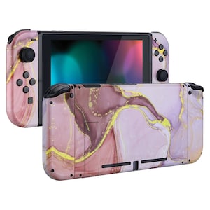 Könnte beinhalten: Eine Nintendo Switch Konsole mit einem pinkfarbenen und goldenen Marmormuster, schwarzen Knöpfen und einem Bildschirm.