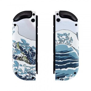 Peut inclure: Une paire de manettes Joy-Con blanches pour Nintendo Switch avec un motif bleu et blanc de la Grande Vague de Kanagawa.