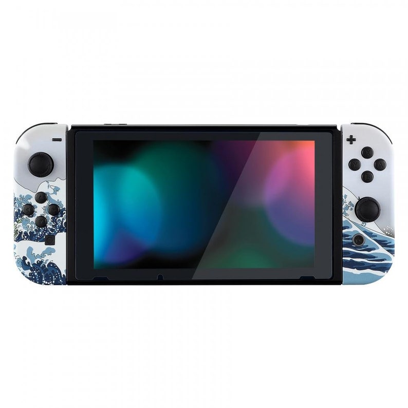 Peut inclure: Une console Nintendo Switch blanche avec un design bleu et blanc de la Grande Vague de Kanagawa. La console est ferm&eacute;e et l'&eacute;cran affiche un d&eacute;grad&eacute; de couleurs.