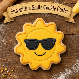 Op de afbeelding: Een gele zonnevormige koek met een zwarte zonnebril en een lachend gezicht. De koek heeft een gele en oranje omtrek. De afbeelding bevat de tekst "Sun with a Smile Cookie Cutter" op een banner.