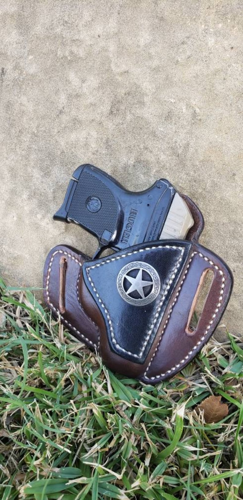 Op de afbeelding: Een bruine leren holster met een zilveren sterontwerp en een zwart pistool erin.