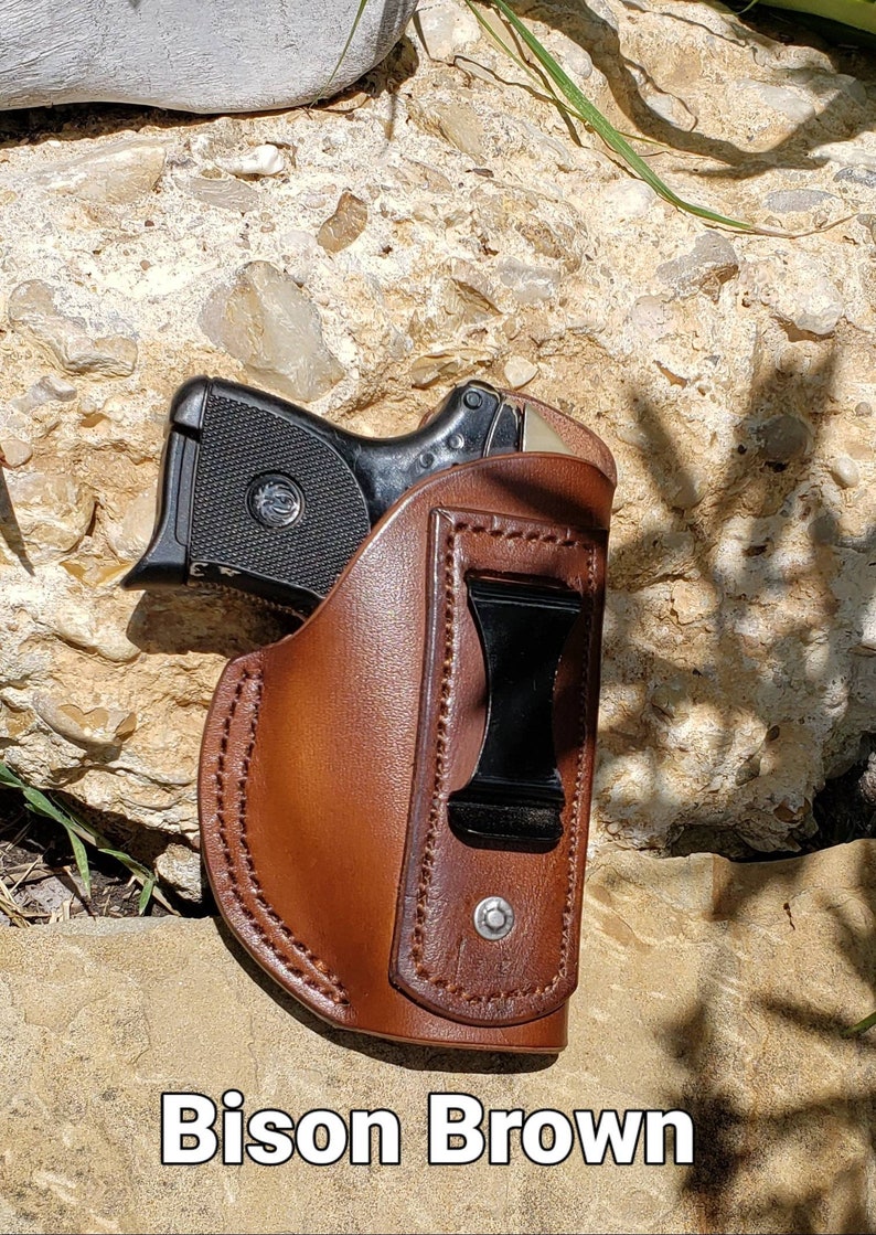 Puede incluir: Una funda de cuero marr&oacute;n con un clip negro para una pistola peque&ntilde;a. La funda est&aacute; etiquetada como "Bison Brown".