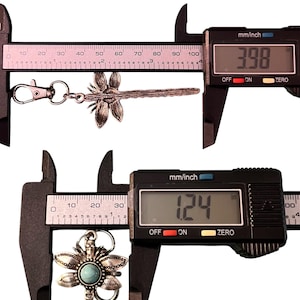 May include: A silver-colored dragonfly keychain, measuring 3.98 inches long, and a silver-colored flower pendant with a turquoise stone, measuring 1.24 inches. Both are displayed with a digital caliper.