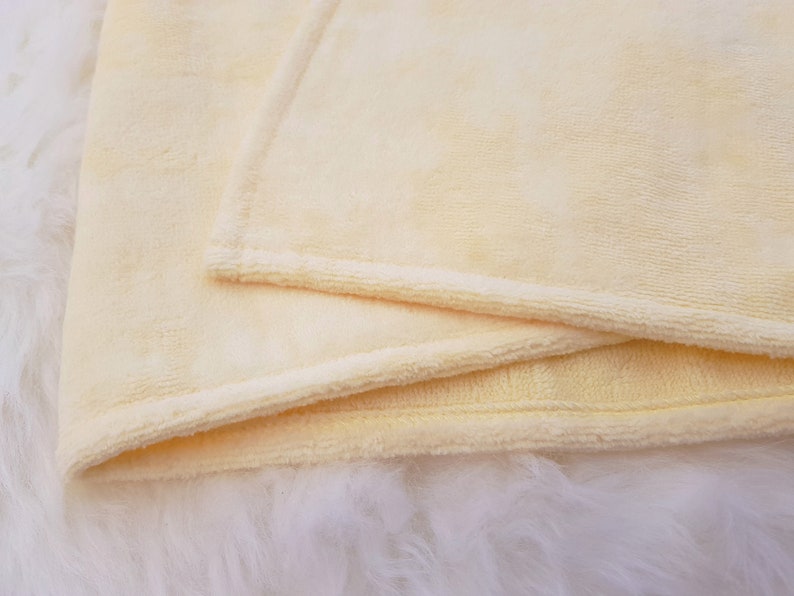 Peut inclure: Une couverture douce de couleur jaune p&acirc;le avec un bord pli&eacute;. La couverture est faite d'un mat&eacute;riau pelucheux et velout&eacute;.