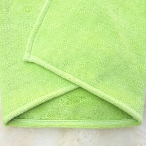 Puede incluir: Una toalla de microfibra verde doblada con un borde cosido.