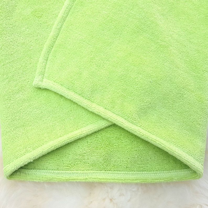 Puede incluir: Una toalla de microfibra verde doblada con un borde cosido.