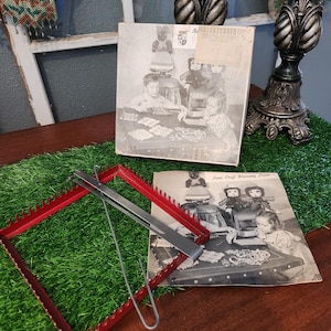 May include: A red metal loom with a silver hook and a black and white photo of children using the loom. The photo includes the text "Loop Craft Weaving Loom".
