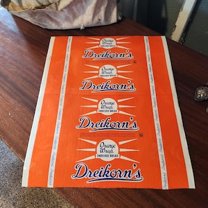 May include: Orange and white bread wrapper with the text "Orange Wrap Enriched Bread Dreikorn's" repeated four times.