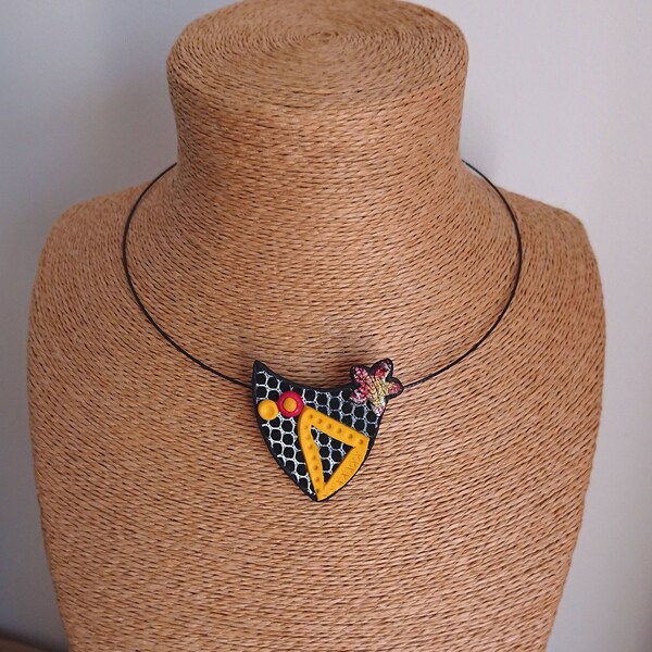 Collier pendentif original, musical, tons rouge et jaune, sur un fond effet dentelle