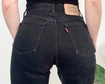 Könnte beinhalten: Schwarze Jeans mit hoher Taille und einem Levi's-Patch auf der Gesäßtasche.